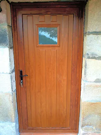 Puerta de entrada en PVC con panel en imitación madera con vidrio de seguridad en Cantabria